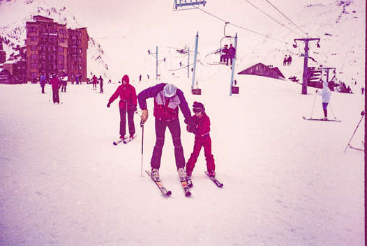 Young Ralph learning to ski with his dad beside a chairlift