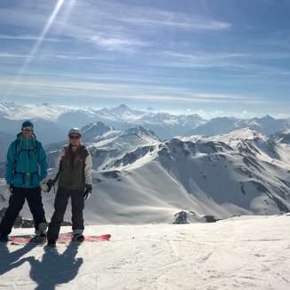 Snowboarders standing on top of a sunny mountain