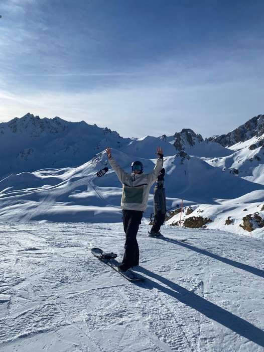 Snowboarder at the top of Palafour beside the Anémone blue piste, with snowy peaks behind, Tignes.