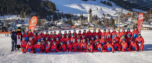 Fürstauer ski instructors in red uniforms on the snow in Saalbach
